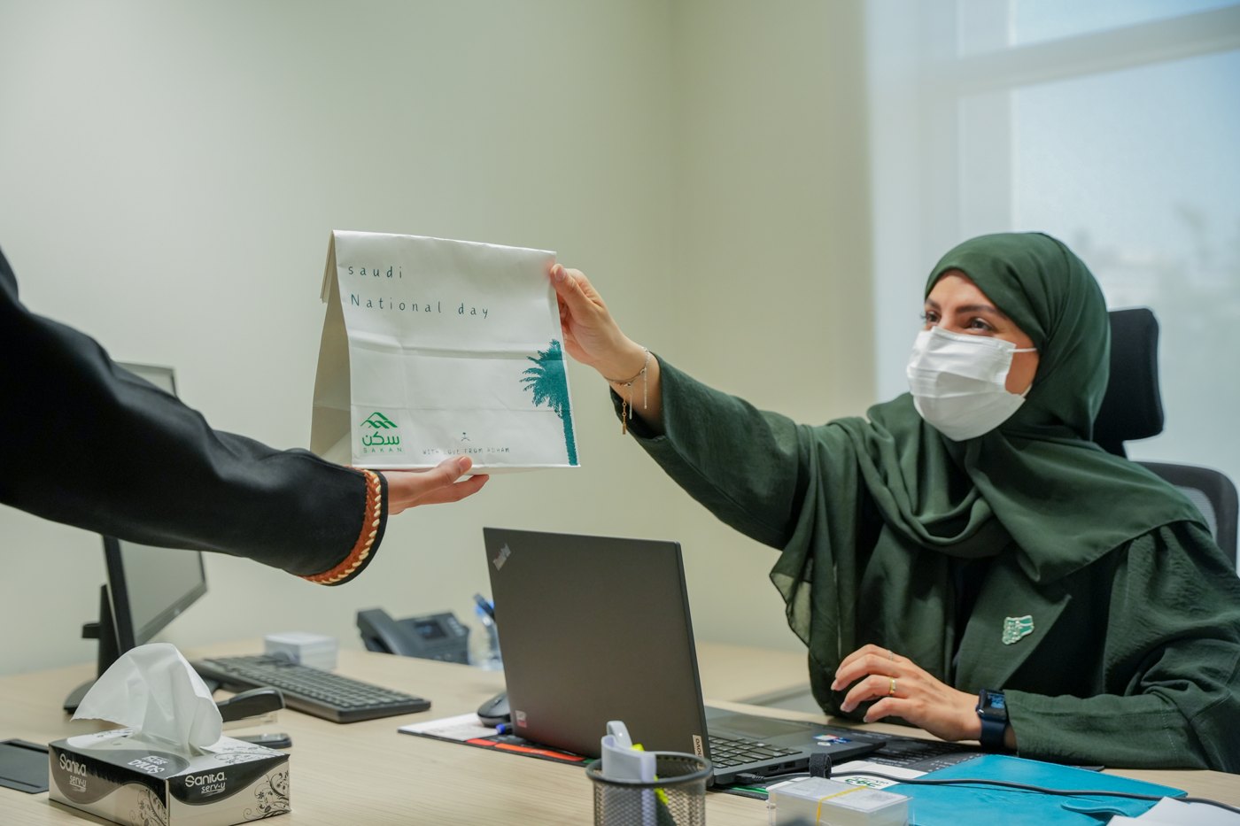 موظفة تستلم هدية اليوم الوطني في مكتب